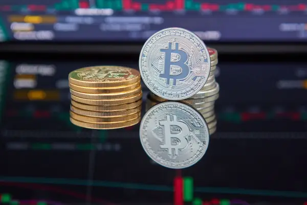 Stacked bitcoin coins in front of a red and green trading chart